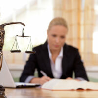 Eine junge Rechtsanwältin sitzt an ihrem Schreibtisch im Büro