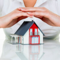 Haus wird beschützt Eine Frau beschützt Ihr Haus und Eigenheim. Gute Versicherung und seriöse Finanzierung beruhigen.